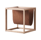 The Brace Side Table showcasing a sturdy elm wood frame paired with built-in leather book storage for stylish organization.