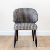 Fino dining chair upholstered in soft grey fabric with a subtle blue tone, featuring a sleek black ash wood frame for a modern luxury look.