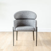 Modern dining chair with grey fabric seat, armrests, and sleek carbon steel frame for comfort and durability.