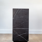 Elegant black marble pedestal with natural veining, styled with a modern sculpture in a minimalist interior.