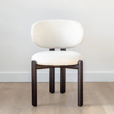 Modern Sofia Dining Chair upholstered in soft white fabric with a minimalist silhouette, perfect for luxury dining spaces.
