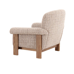 Modern lounge armchair with soft curves, textured upholstery, and natural timber detailing, ideal for living rooms and reading spaces.