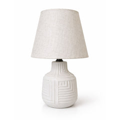 A compact ceramic table lamp with subtle carved line detailing and rounded form