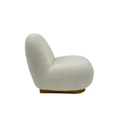Luxurious boucl?? fabric armchair with rounded form and metal base, offering cloud-like comfort in a modern interior setting.