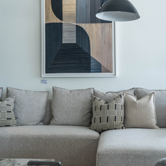 Stylish modern corner sofa upholstered in soft fabric with intricate arm design, perfect for living room or open-plan spaces.