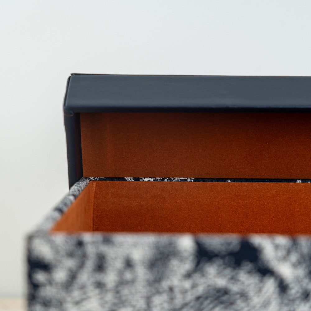 Designer keepsake container showcasing botanical patterns and a dark, sleek lid.