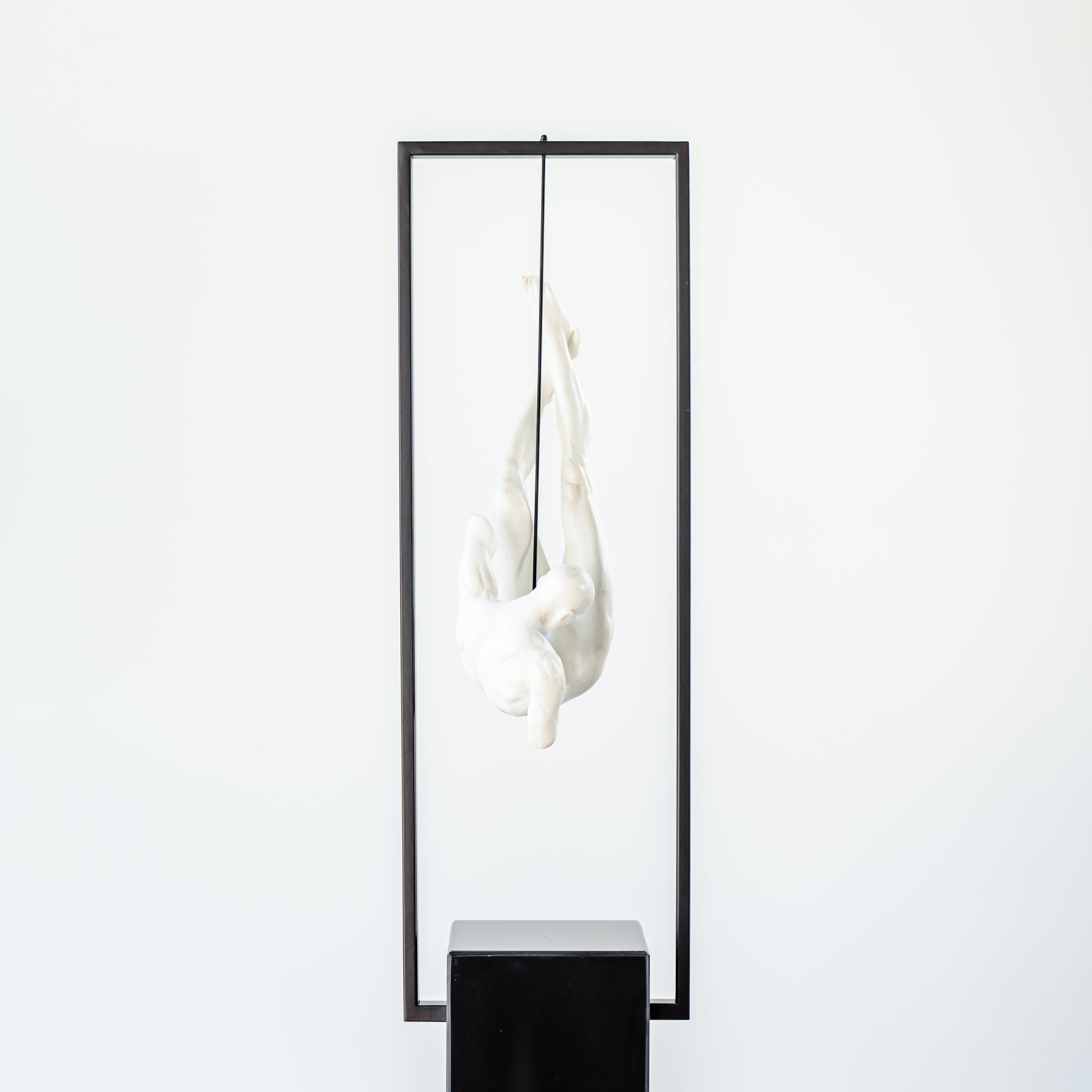 Art resin sculpture of man suspended in black metal frame