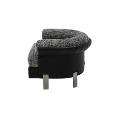 The Elias Armchair positioned in a contemporary living room, highlighting its bold curved design, cozy seating, and high-end material combination of woven fabric and leather.