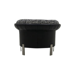 The Elias Armchair styled as a reading chair, featuring plush woven fabric, a rounded sculptural shape, and genuine leather accents for a refined, luxurious touch.