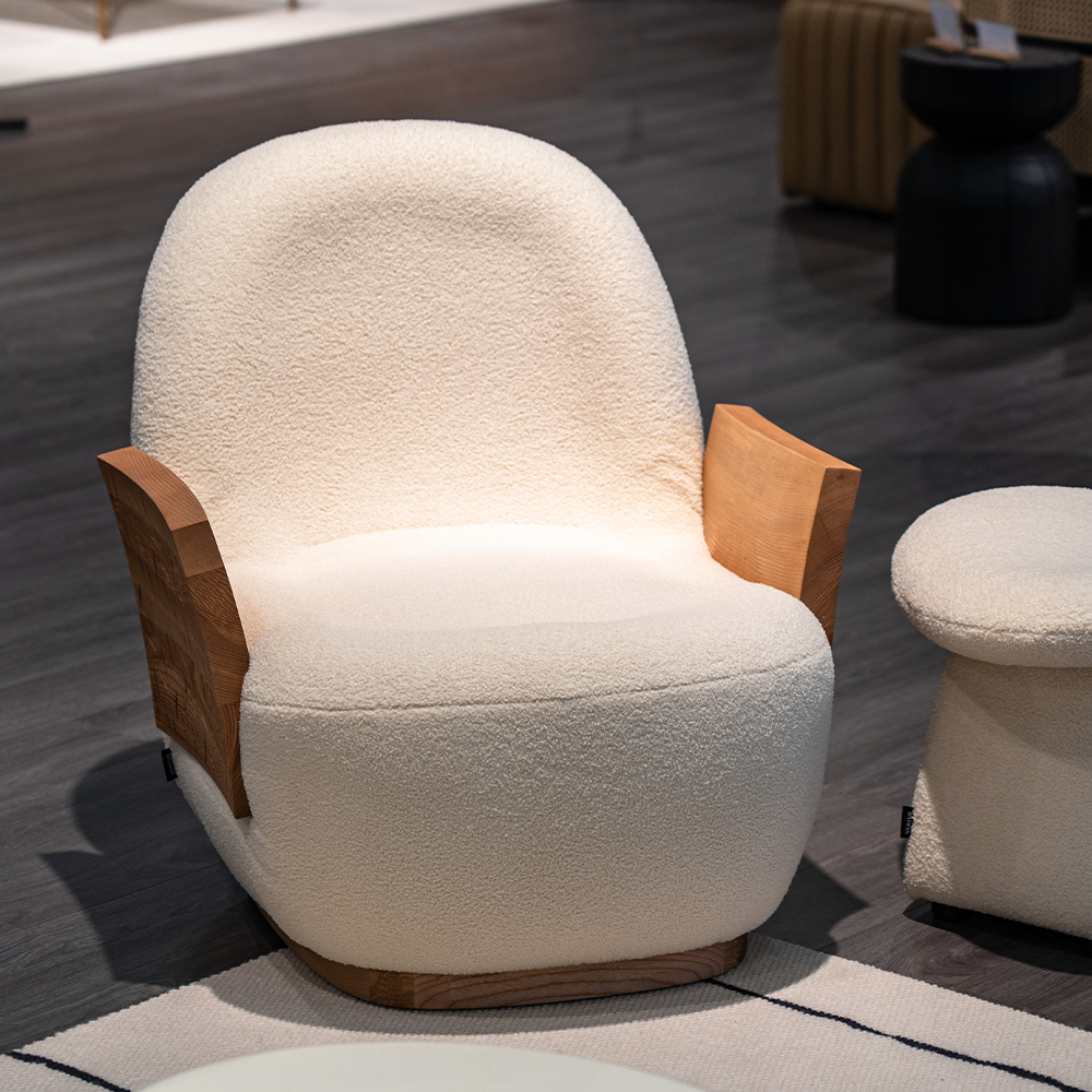 Comfortable modern reading chair with chenille fabric, curved backrest, and warm wooden side details.