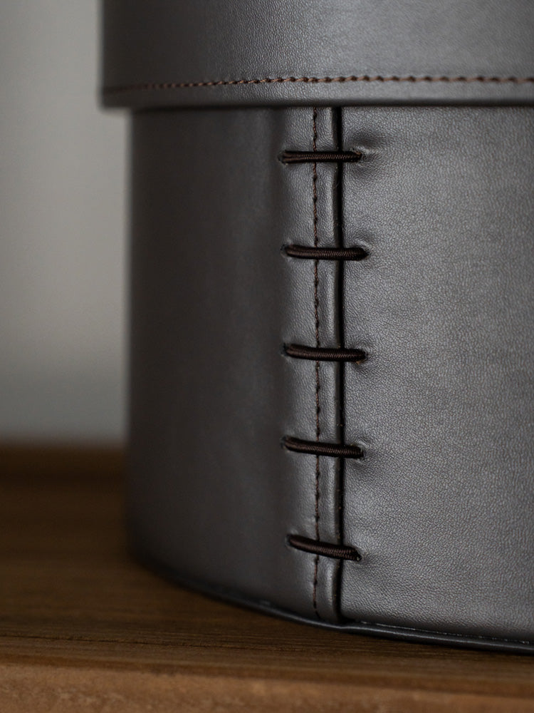 Stylish medium and large circular storage boxes made from durable hand-woven bridle leather, ideal for storing everyday items or displaying decorative pieces in contemporary and minimalist spaces.