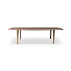 Close-up of the Bohne Dining Table featuring a rich walnut-colored veneer top and bronze brushed stainless steel legs in a modern dining room.