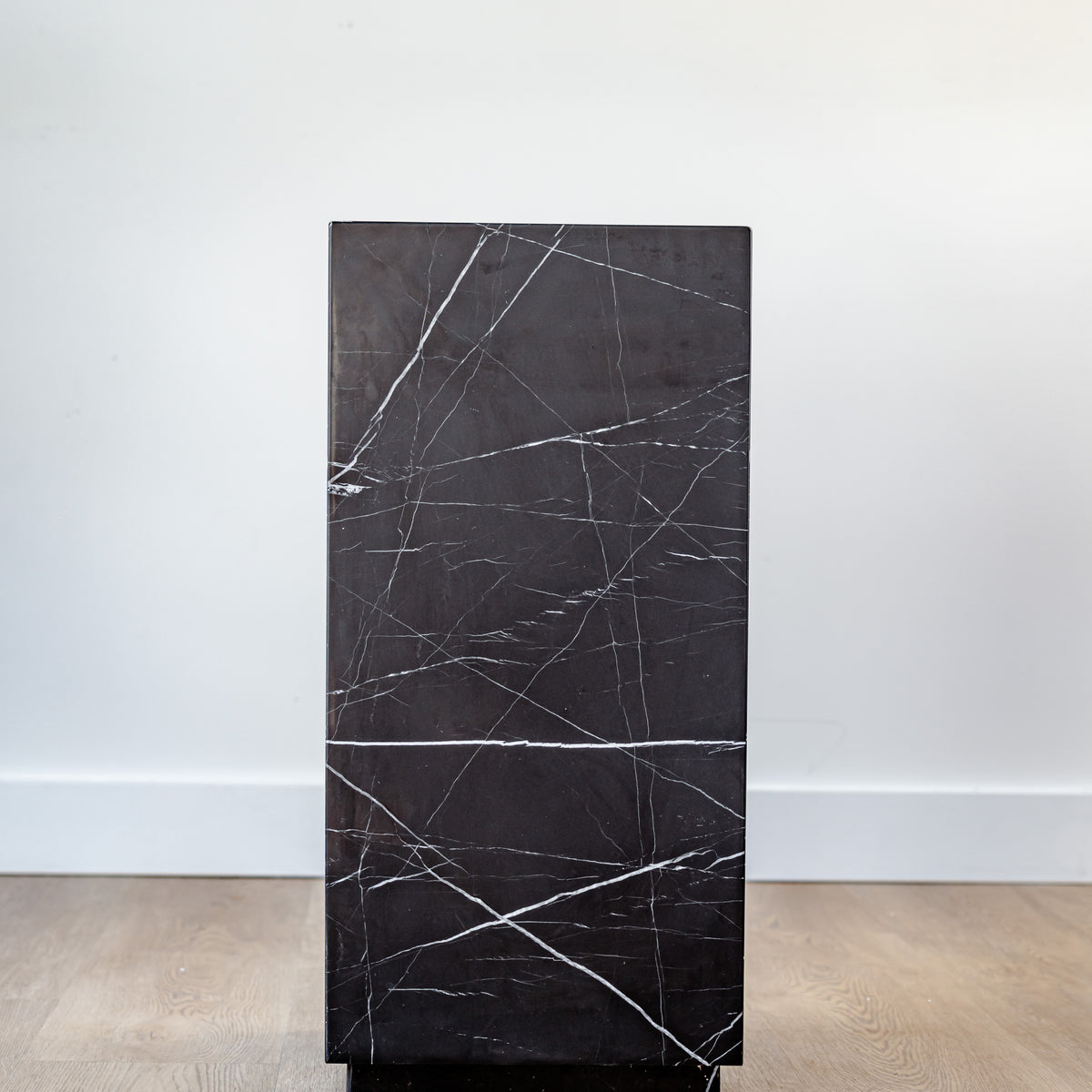 Elegant black marble pedestal with natural veining, styled with a modern sculpture in a minimalist interior.