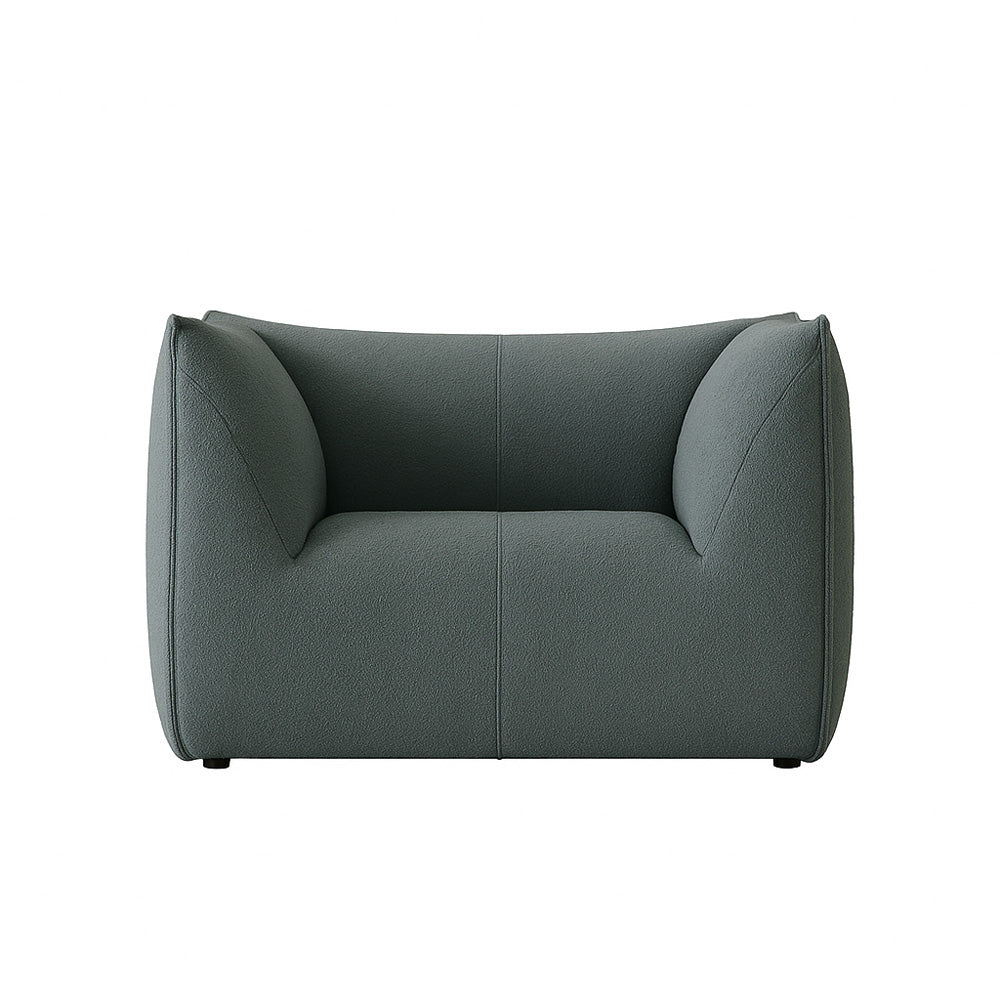 The Panos Armchair in striking green upholstery, designed with a sculptural silhouette and plush seat, adding a colorful statement to contemporary home decor.