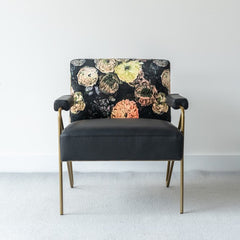 Elegant accent chair with a luminous gold metal frame, plush leather seat, and velvet floral backrest, perfect for sophisticated interiors.
