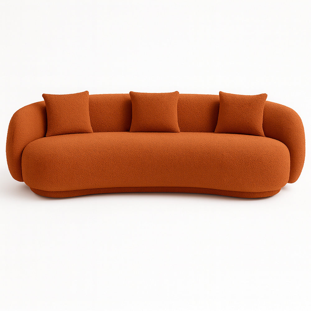 The Zoi 3-Seater Sofa in bold burnt orange boucl?? fabric, designed with soft curves and three matching cushions, creating a striking focal point in a modern interior.