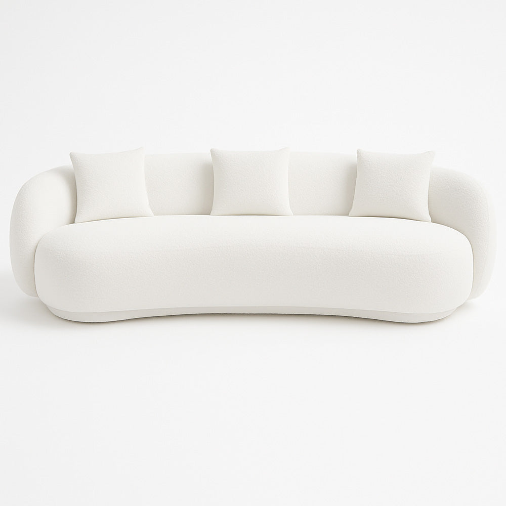 The Zoi 3-Seater Sofa in white textured bouclé fabric, featuring a sculptural curved design and three matching cushions, styled in a bright modern living room.