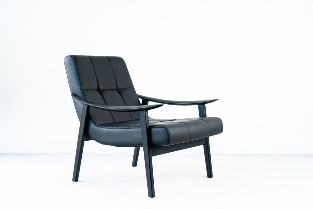 Designer Trani armchair in black faux leather with ashwood legs, ergonomic lounge seating for interiors