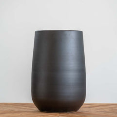 Medium black ceramic planter with handmade textured surface and drainage hole, suitable for indoor and outdoor plants.