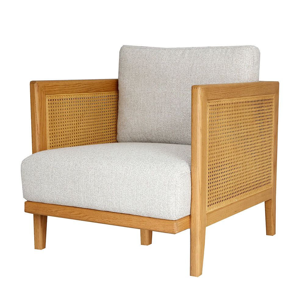 Lisbon Armchair with solid oak frame, rattan detailing, and soft linen upholstery in natural tones.
