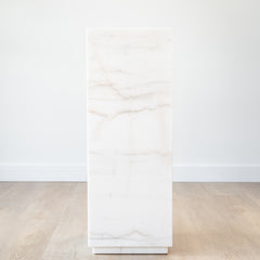 Modern marble plinth with a polished white stone finish, styled as a pedestal for sculpture in a minimalist living room.