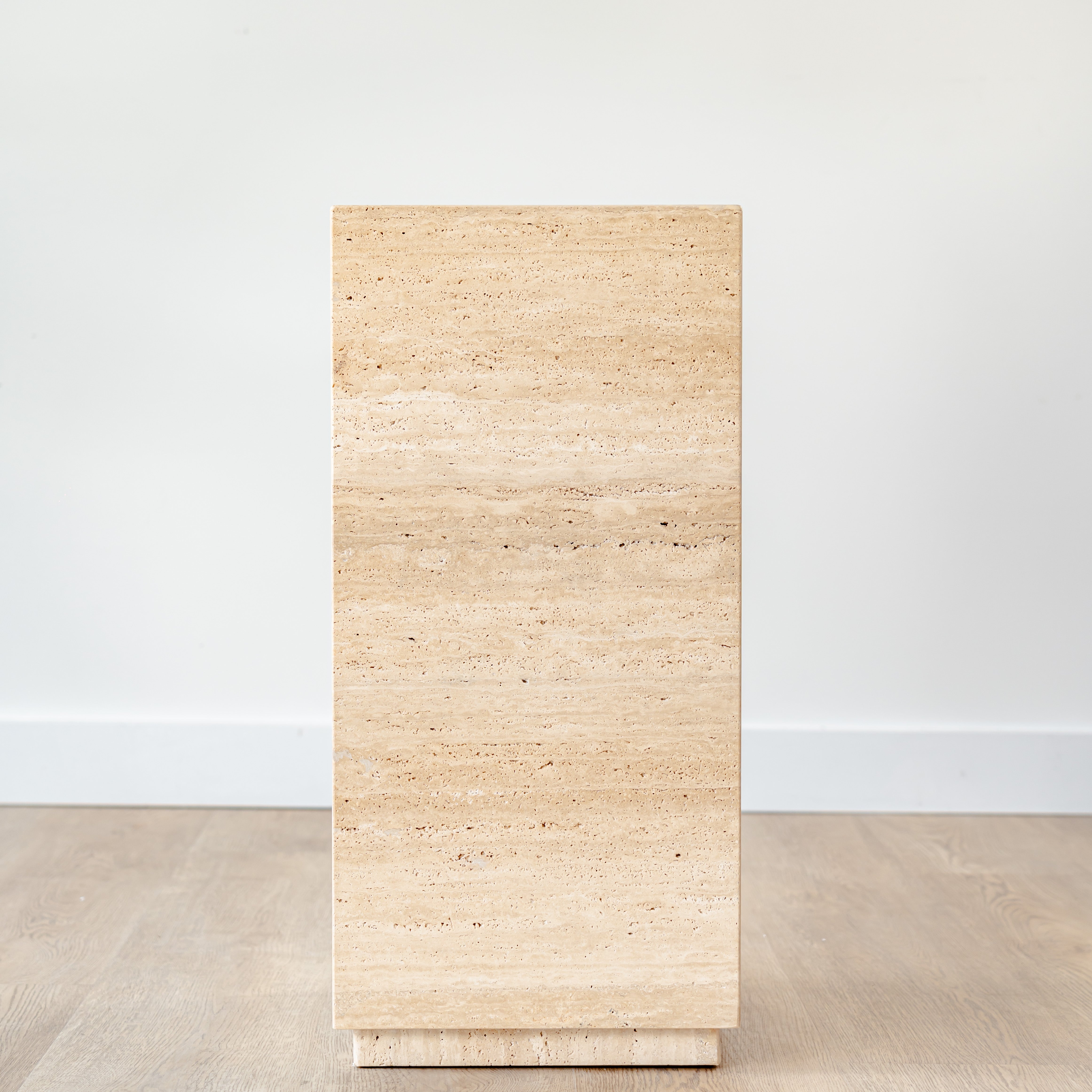 Minimalist travertine display stand featuring warm earth tones and clean lines, placed in a contemporary space.