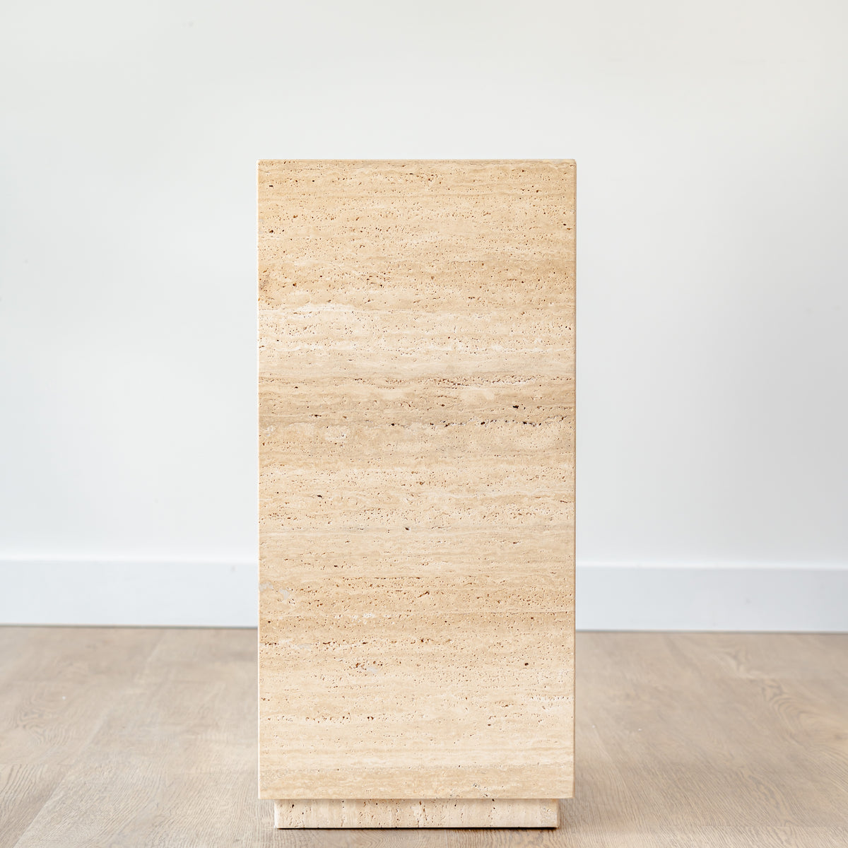 Minimalist travertine display stand featuring warm earth tones and clean lines, placed in a contemporary space.