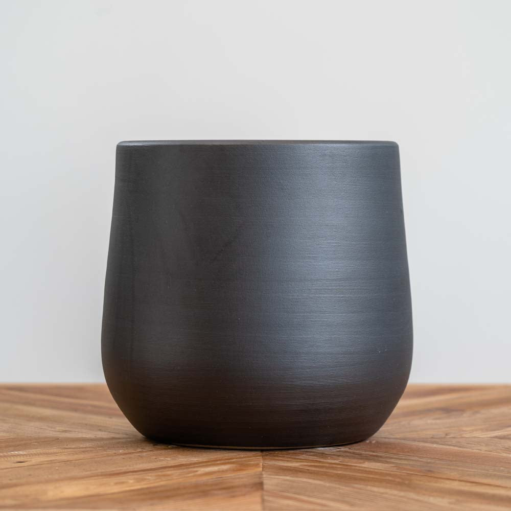 Small black ceramic planter with handmade textured surface, built-in drainage hole, suitable for indoor and outdoor plants.